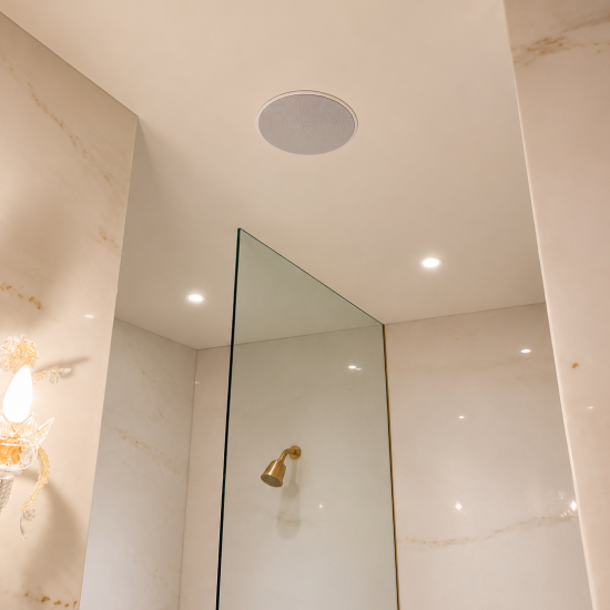 Enceinte encastrée au plafond dans une salle de bains haut de gamme pour une diffusion musicale discrète et immersive.